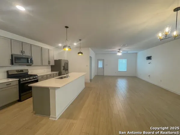 a large kitchen with kitchen island a sink dishwasher a stove and a refrigerator with wooden floor