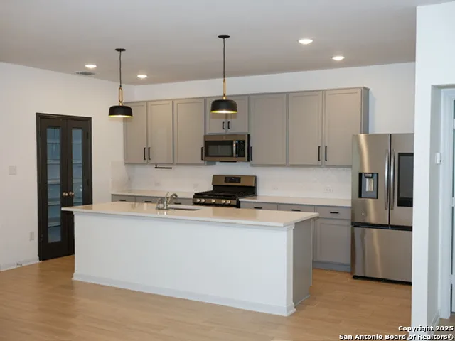 a kitchen with stainless steel appliances granite countertop a refrigerator a stove a sink and a microwave