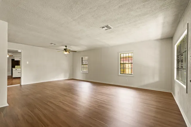 an empty room with wooden floor and windows