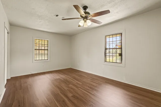 a view of an empty room with wooden floor and a window