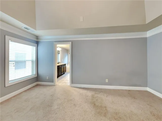 a view of an empty room with a window and a kitchen