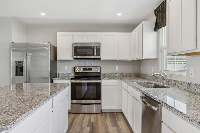 a kitchen with stainless steel appliances granite countertop a sink stove microwave and refrigerator