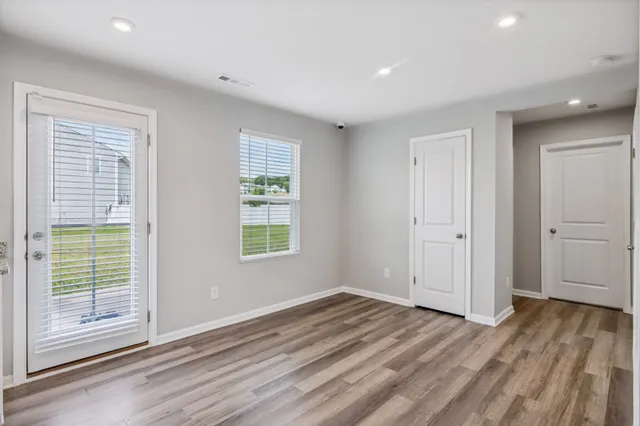 a view of empty room with wooden floor and fan
