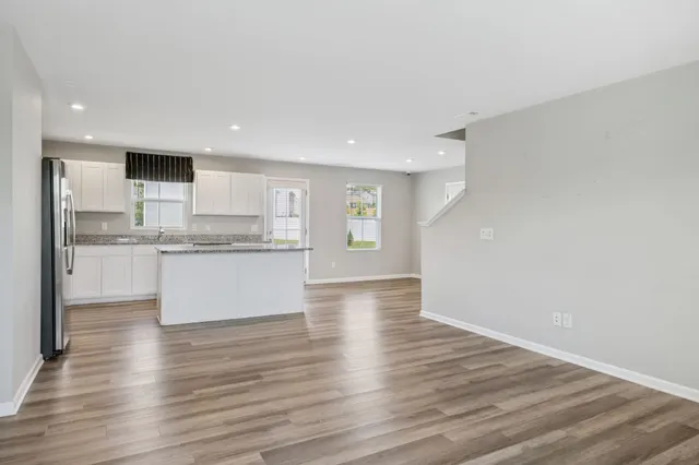 a large white kitchen with kitchen island a sink dishwasher a stove and a refrigerator with wooden floor