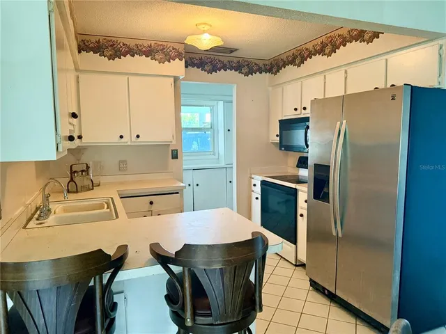 a kitchen with stainless steel appliances granite countertop a refrigerator a sink a stove and white cabinets