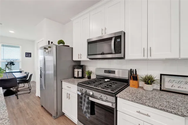 a kitchen with stainless steel appliances granite countertop a stove microwave refrigerator and sink