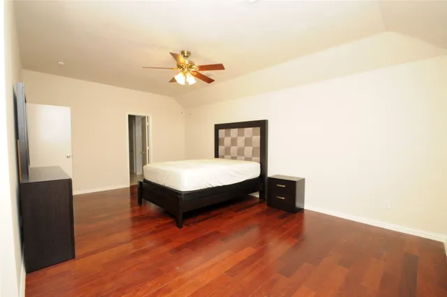 a spacious bedroom with a bed and wooden floor