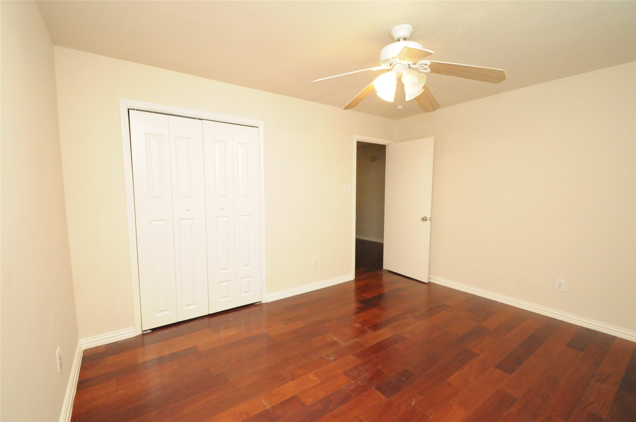 16127 Eaglewood Spring Court Houston, TX 77083 - Photo 22 of 31 an empty room with a chandelier fan and wooden floor