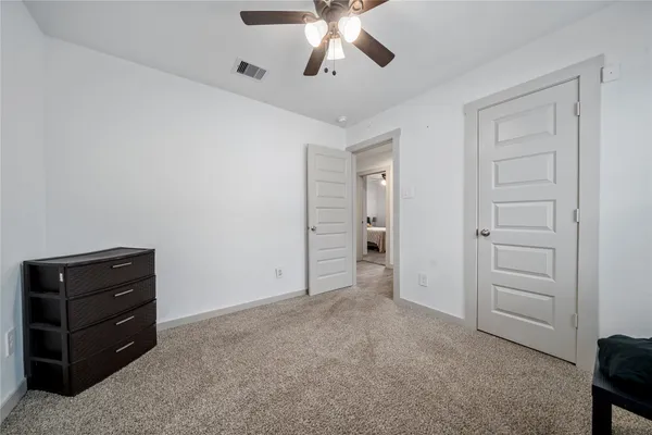 a view of an empty room with cabinet and a ceiling fan