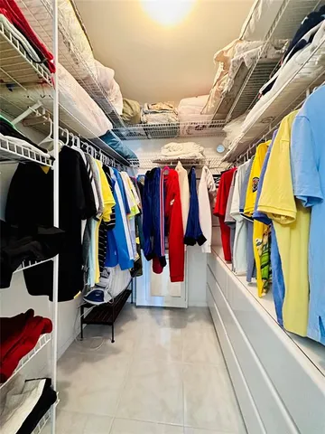 a view of walk in closet with clothes and shoes