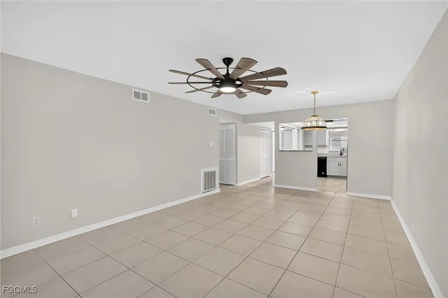 a view of an empty room and chandelier fan