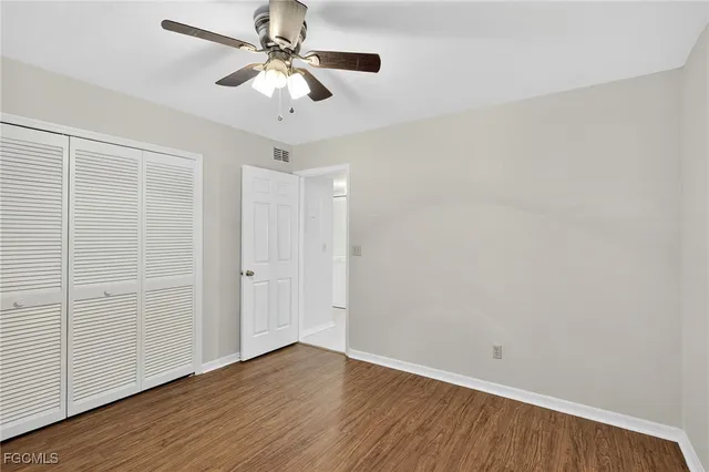 an empty room with wooden floor chandelier fan and closet area