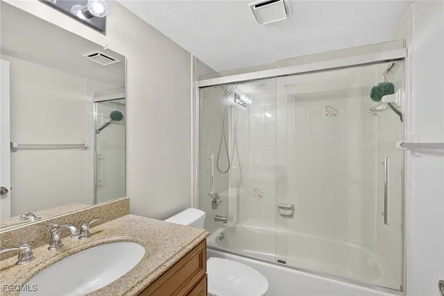 a bathroom with a granite countertop bathtub shower sink vanity and toilet