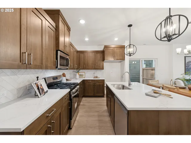 a kitchen with stainless steel appliances a sink a stove a refrigerator and cabinets