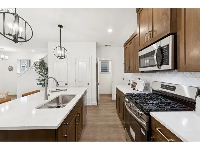 a kitchen with stainless steel appliances a stove a sink and a microwave