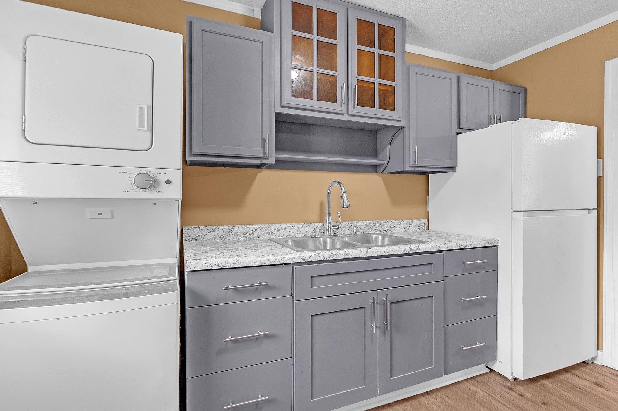 3186 Alta Road Memphis, TN 38109 - Photo 7 of 14 Kitchen area featuring gray cabinetry with brushed nickel pulls, a double basin sink with a high-arc faucet, and granite-look countertops