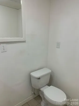 a white toilet sitting next to a white wall