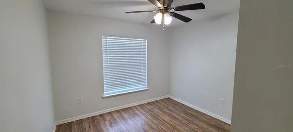 an empty room with windows and fan