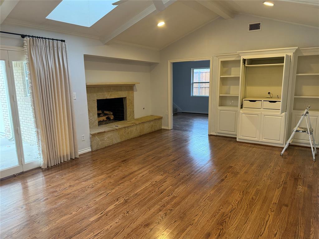 4916 Sugar Mill Road Dallas, TX 75244 - Photo 4 of 18 Unfurnished living room with dark wood finished floors, a fireplace, a skylight, and ornamental molding