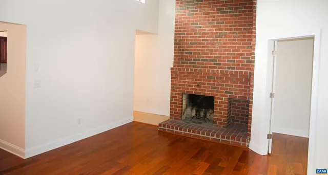 a view of a livingroom with wooden floor and a fireplace