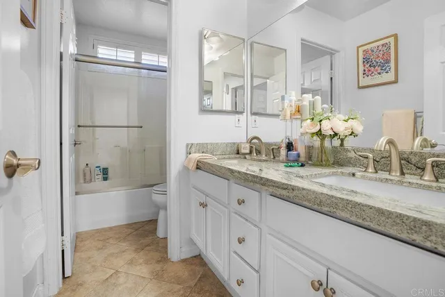 a bathroom with a granite countertop sink a mirror a bathtub and shower