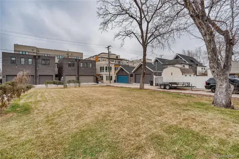 a view of pool with large trees and cars parked