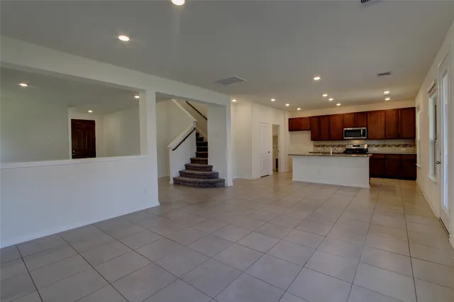 a view of kitchen with stainless steel appliances granite countertop a refrigerator and a stove top oven