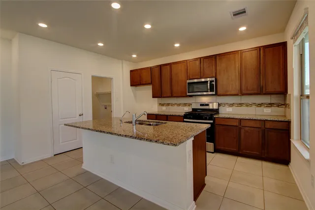 a kitchen with stainless steel appliances granite countertop a stove a sink a microwave and a refrigerator