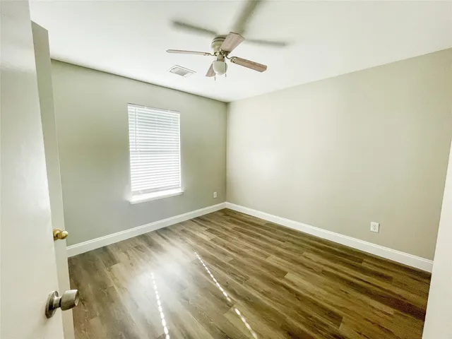an empty room with a window and a ceiling fan