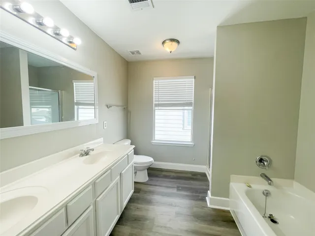 a spacious bathroom with a tub sink and mirror