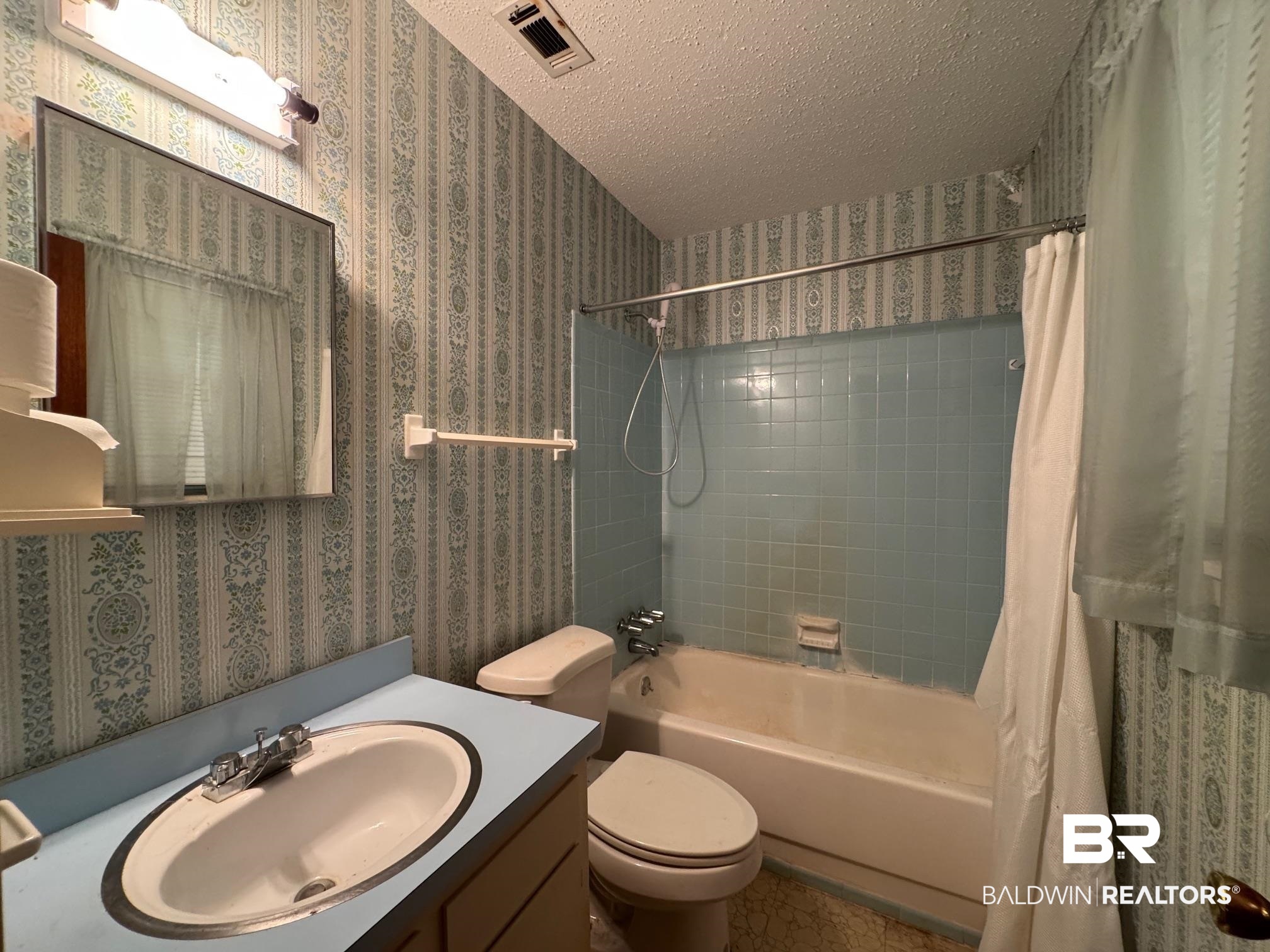 5198 Lancelot Drive Mobile, AL 36619 - Photo 18 of 30 Bathroom featuring wallpapered walls, a textured ceiling, shower / tub combo with curtain, and vanity