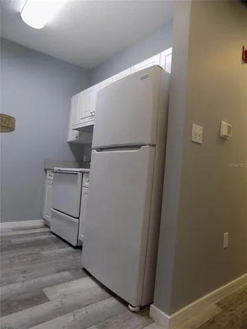 a view of a refrigerator in kitchen and an empty room