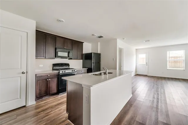 a kitchen with stainless steel appliances granite countertop a stove a refrigerator a sink dishwasher and a oven with wooden floor