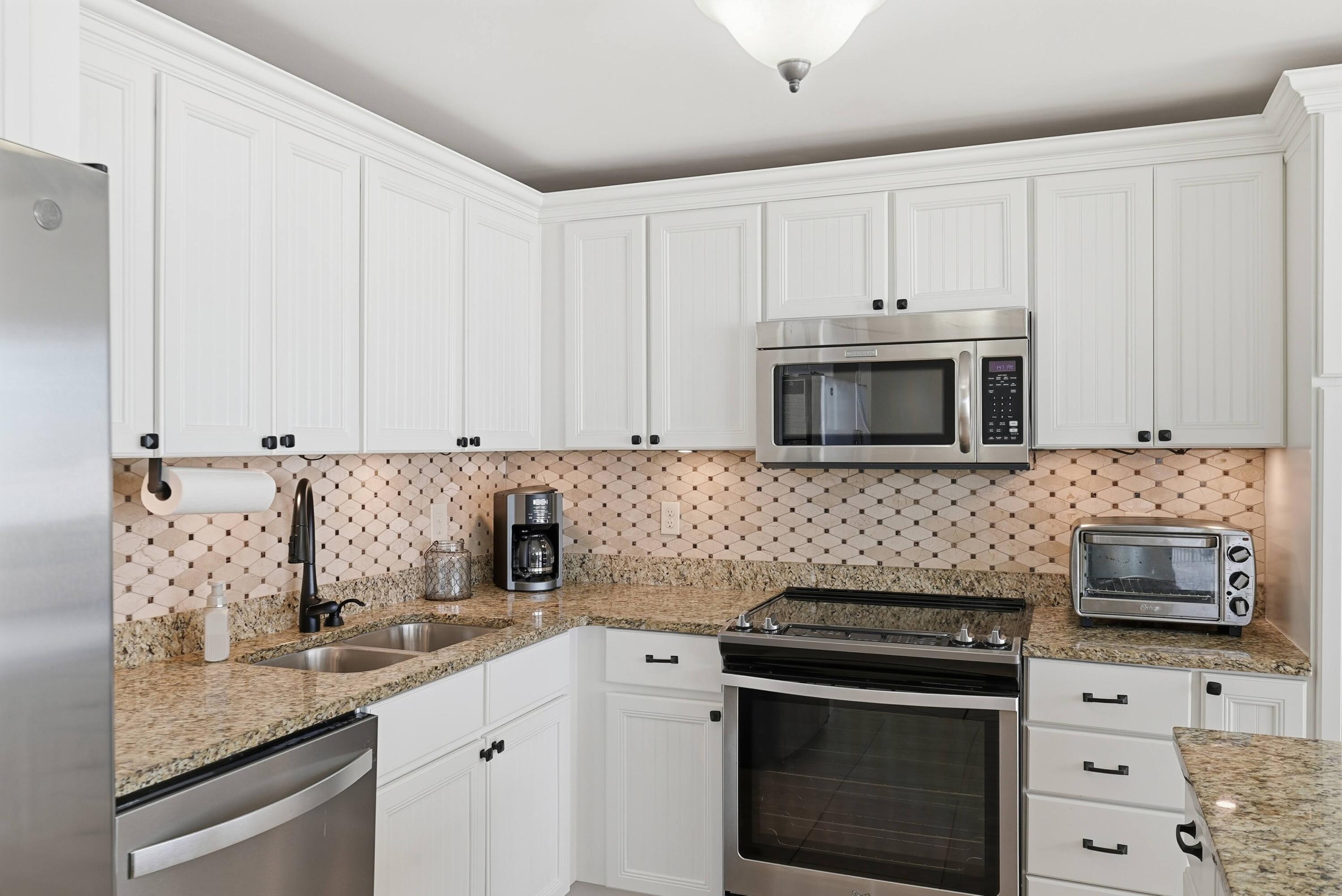 11619 Front Beach Road, Unit 212 Panama City Beach, FL 32407 - Photo 15 of 63 a kitchen with granite countertop white cabinets and stainless steel appliances