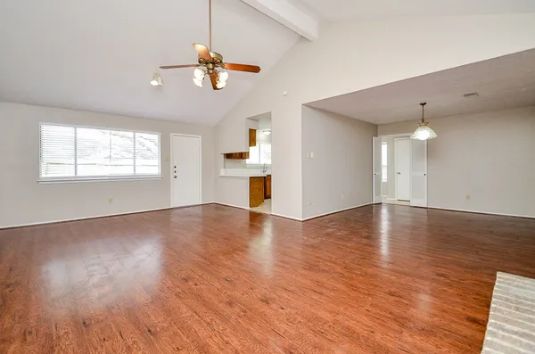 an empty room with wooden floor chandelier and windows
