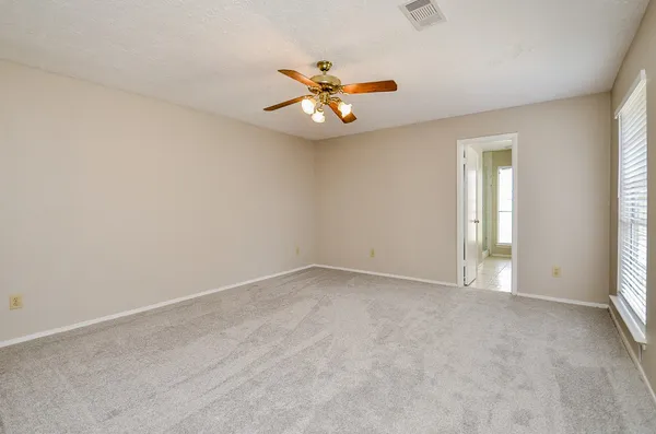 an empty room with chandelier fan and windows