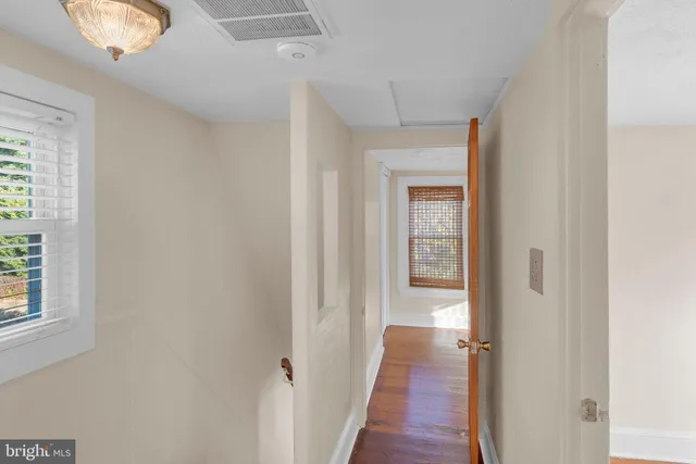 a view of a hallway with wooden floor and closet