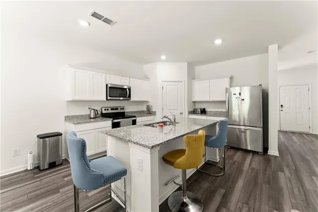 a kitchen with a dining table chairs refrigerator and microwave