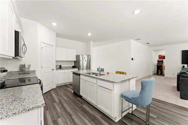 a kitchen with granite countertop white cabinets and stainless steel appliances