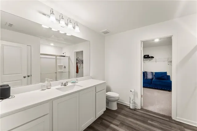 a spacious bathroom with a double vanity sink a mirror and a toilet