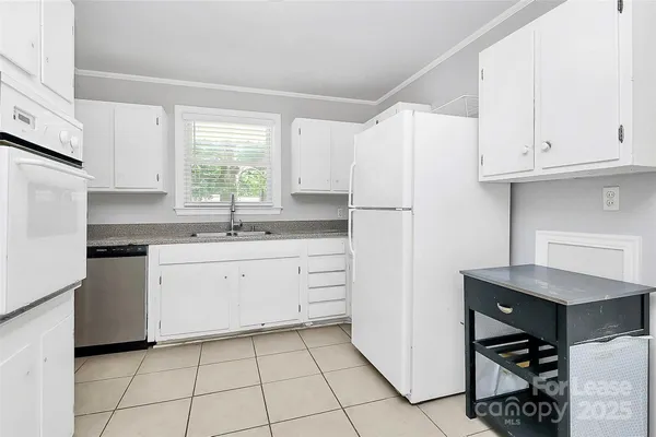 a kitchen with white cabinets appliances and a window