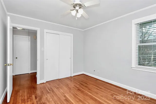 a view of empty room with wooden floor and fan