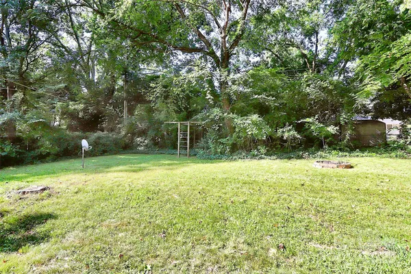 a backyard of a house with lots of plants and large tree