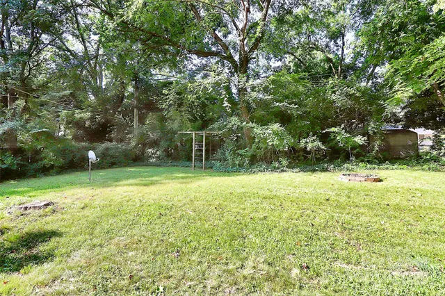 a backyard of a house with lots of plants and large tree