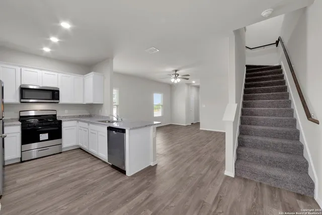 a kitchen with granite countertop a refrigerator and a stove top oven