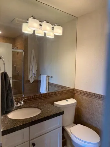 a bathroom with a granite countertop toilet sink and mirror