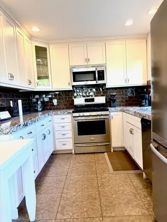 a kitchen with stainless steel appliances granite countertop a stove a sink and a microwave