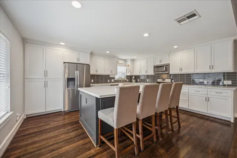 a kitchen with stainless steel appliances refrigerator dining table and chairs