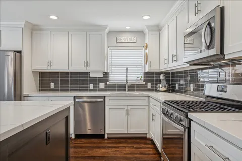 a kitchen with stainless steel appliances granite countertop a stove and white cabinets