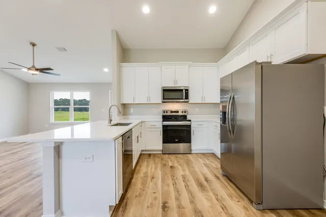 a kitchen with a refrigerator a sink dishwasher with a oven and a refrigerator with wooden floor